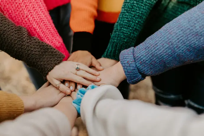 Foto door Hannah Busing op Unsplash Personen die hun handen samen brengen